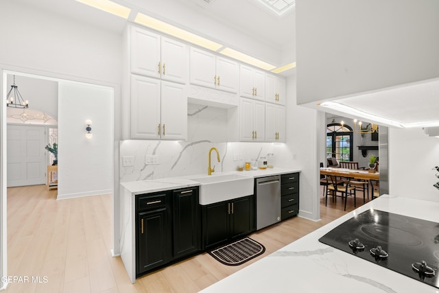 kitchen with white cabinets, stainless steel dishwasher, a sink, a chandelier, and dark cabinetry