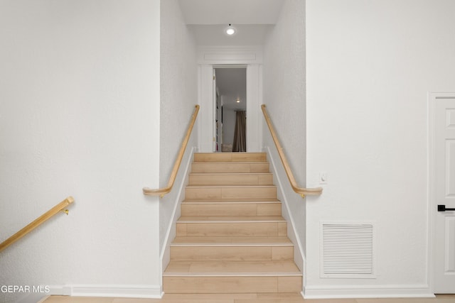 stairway featuring baseboards, wood finished floors, and visible vents