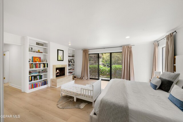 bedroom with crown molding, light wood finished floors, a premium fireplace, visible vents, and recessed lighting
