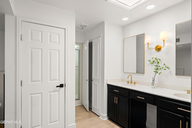 full bath with recessed lighting, double vanity, wood finished floors, and a sink