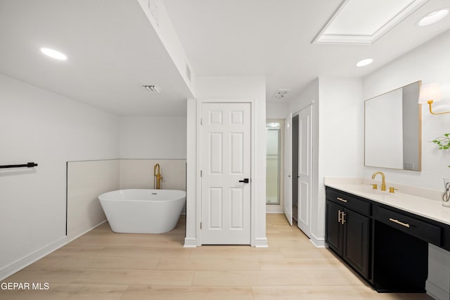 bathroom featuring visible vents, wood finished floors, vanity, and a freestanding bath