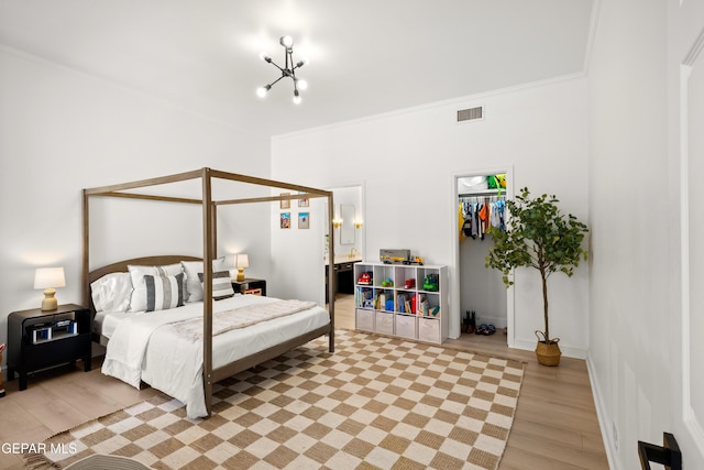 bedroom with visible vents, an inviting chandelier, light wood-style floors, a closet, and ornamental molding