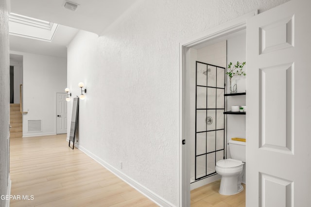 hallway with visible vents, baseboards, wood finished floors, and stairs