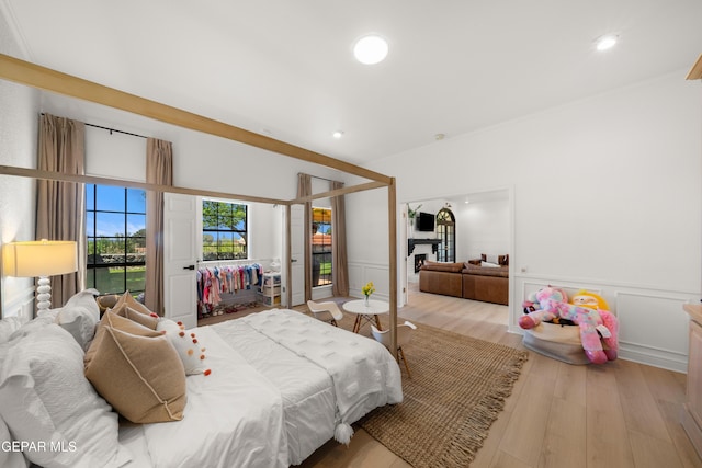 bedroom featuring a wainscoted wall, wood finished floors, recessed lighting, and a decorative wall