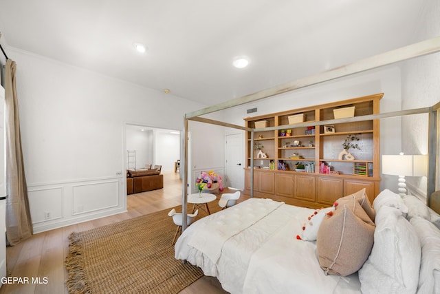 bedroom featuring wainscoting, visible vents, and light wood-style flooring