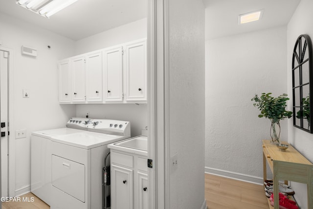 washroom with baseboards, cabinet space, light wood-style floors, and independent washer and dryer