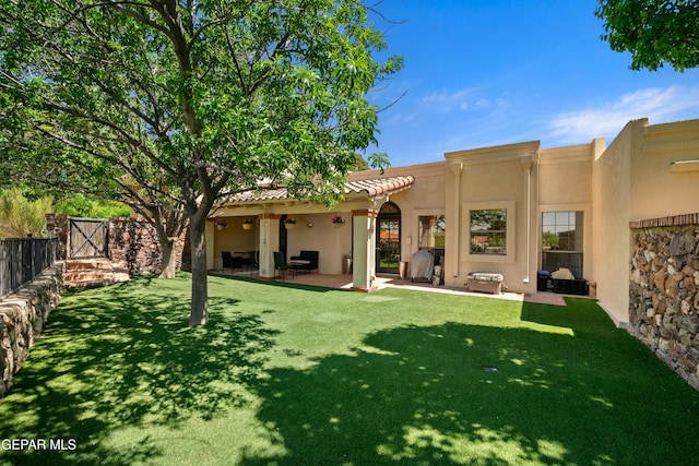 rear view of house featuring fence, a lawn, a patio area, and stucco siding