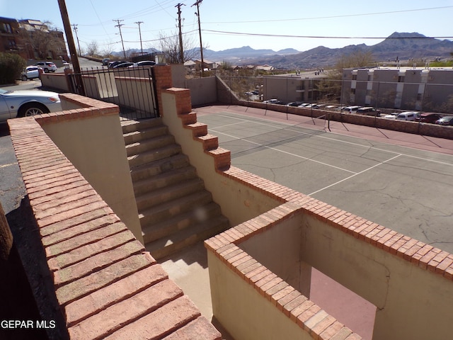 view of pool with a tennis court, fence, and a mountain view