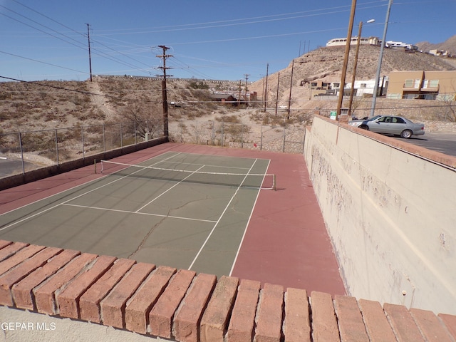 view of tennis court with fence and a mountain view