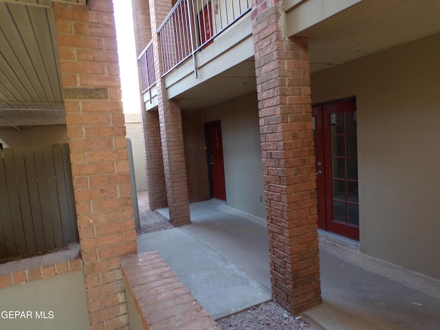view of exterior entry featuring brick siding and a balcony
