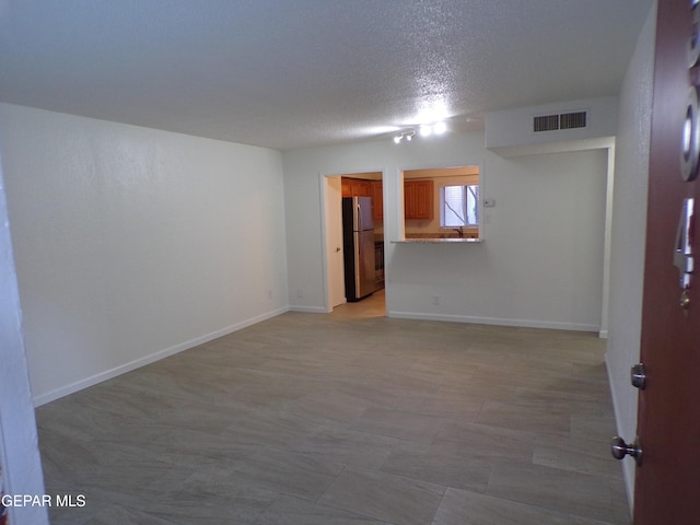 empty room featuring baseboards, visible vents, and a textured ceiling