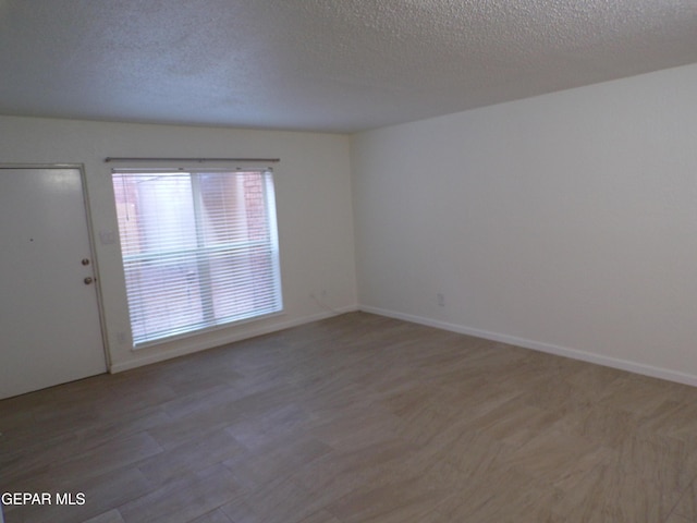 unfurnished room with a textured ceiling and baseboards