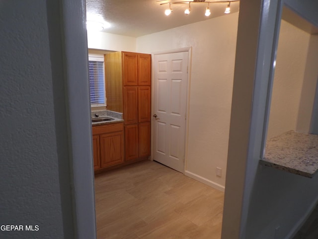 hallway with baseboards, a sink, and light wood-style flooring