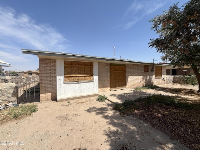 view of front of property featuring brick siding, fence, and a patio