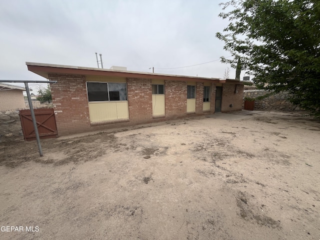 rear view of house with brick siding and a gate