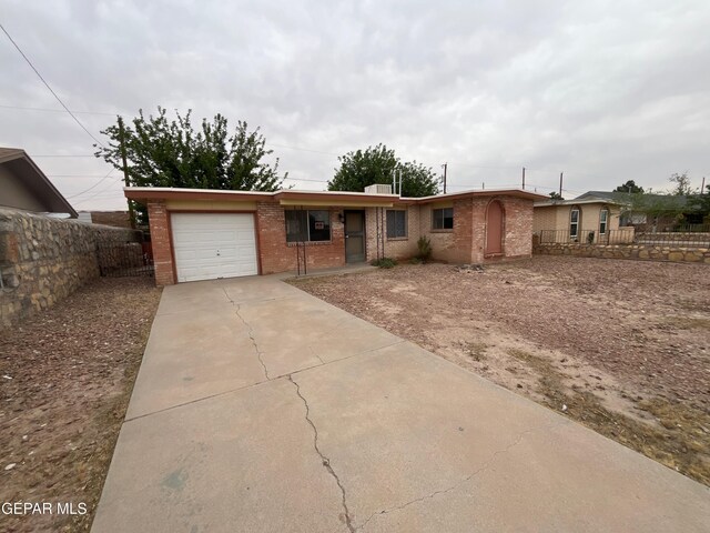 single story home featuring a garage, driveway, brick siding, and fence