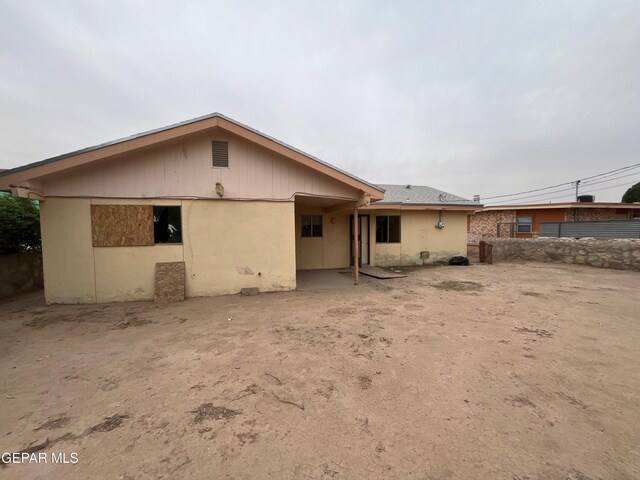 rear view of house with fence and stucco siding