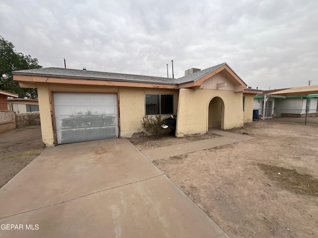 ranch-style house featuring stucco siding, an attached garage, fence, and driveway