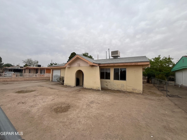 exterior space with cooling unit, driveway, fence, an attached garage, and stucco siding