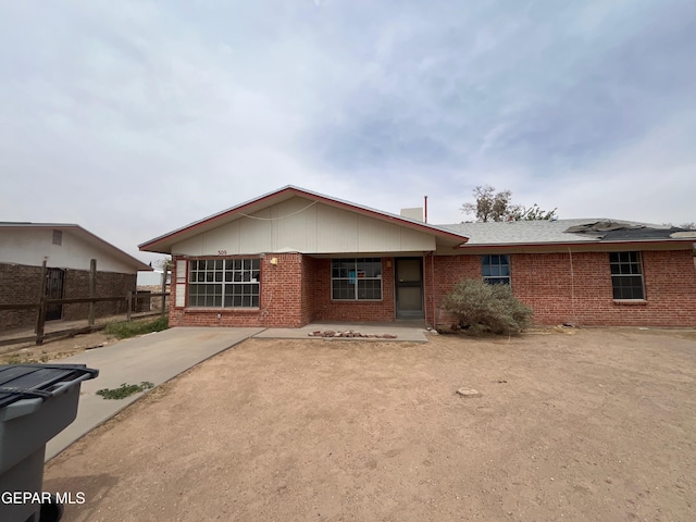 rear view of house featuring brick siding, fence, and a patio