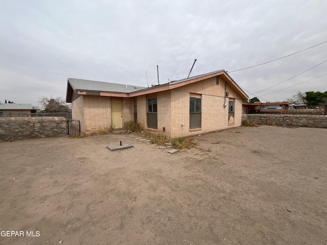 rear view of house with fence and brick siding