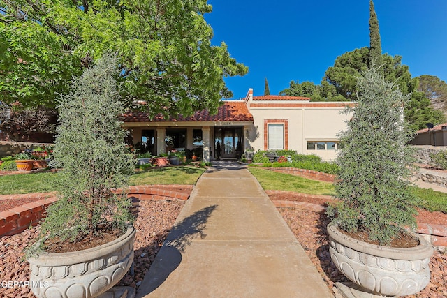mediterranean / spanish-style house with stucco siding, a tiled roof, and a front yard