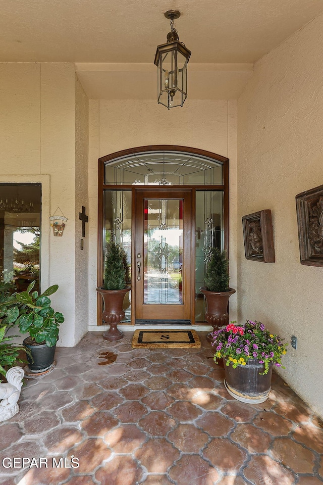 view of exterior entry featuring stucco siding and covered porch