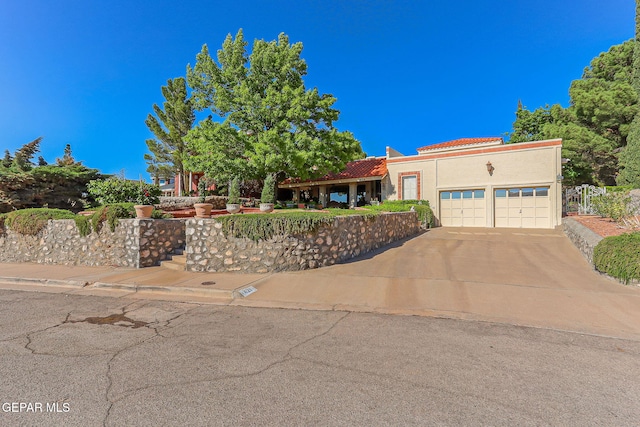 view of front facade with concrete driveway, an attached garage, a tile roof, and stucco siding
