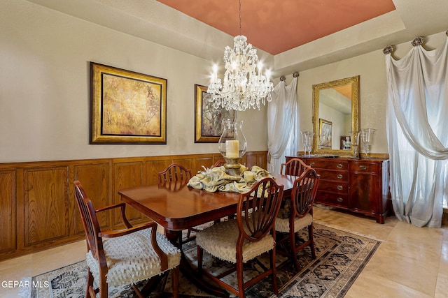 dining room with a raised ceiling, wainscoting, and a chandelier