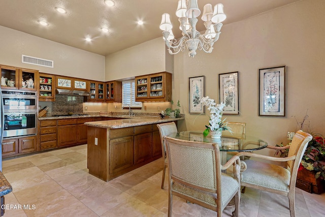 kitchen featuring visible vents, double oven, high vaulted ceiling, brown cabinets, and a sink