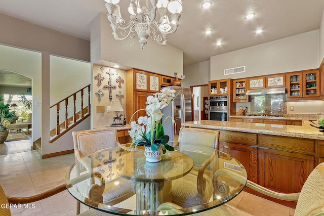 dining space with light tile patterned flooring, a notable chandelier, stairs, a towering ceiling, and visible vents