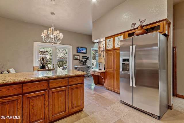 kitchen with light countertops, brown cabinetry, stainless steel refrigerator with ice dispenser, and a chandelier