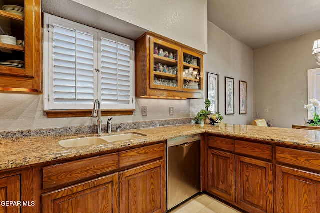 kitchen with brown cabinets, light stone counters, a sink, dishwasher, and glass insert cabinets