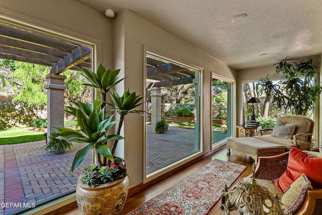 sunroom / solarium featuring a textured ceiling and wood finished floors
