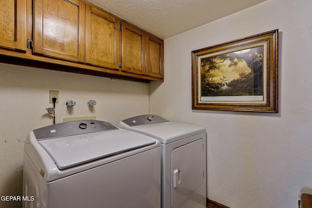 washroom with a textured ceiling, cabinet space, and washing machine and clothes dryer