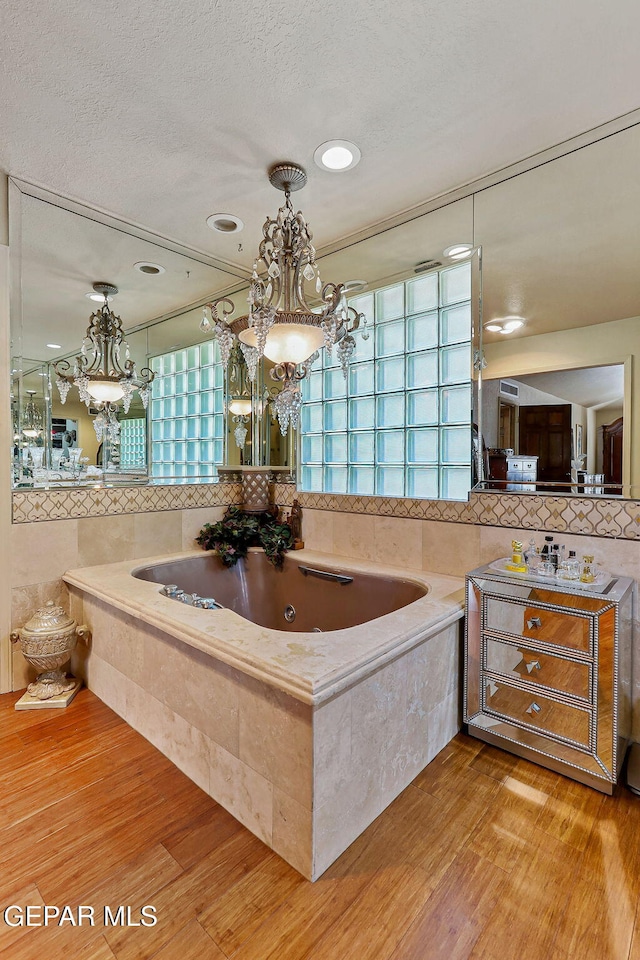 bathroom with a whirlpool tub, a textured ceiling, decorative backsplash, and wood finished floors