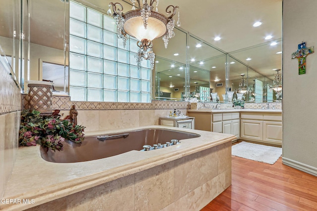 full bath featuring a garden tub, visible vents, wood finished floors, vanity, and recessed lighting