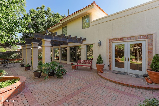 rear view of property featuring a patio, french doors, a tile roof, and stucco siding
