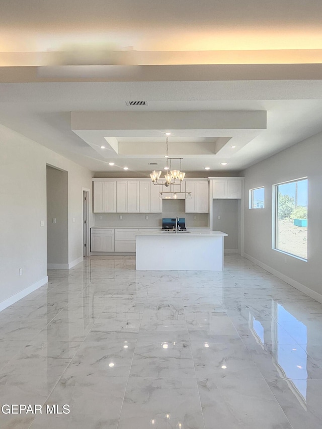 474 Sylvia Ct, Socorro, TX 79927 - kitchen with a tray ceiling, white cabinets, a center island with sink, a chandelier, and light marble finish flooring