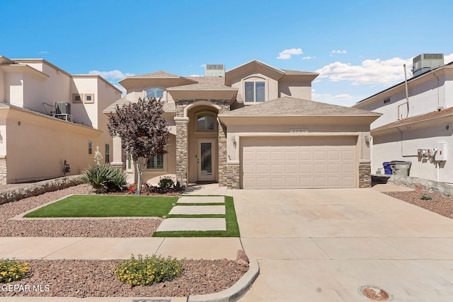mediterranean / spanish house featuring an attached garage, driveway, stucco siding, and stone siding