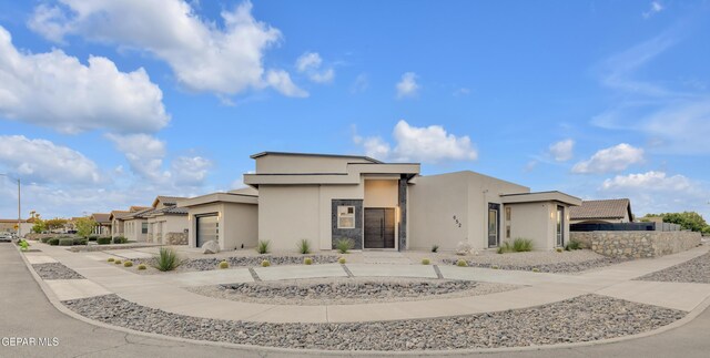 view of front of home with a garage, stucco siding, driveway, and a residential view