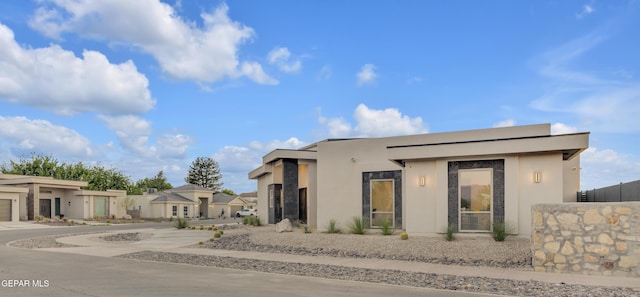 view of front facade with driveway, a residential view, and stucco siding