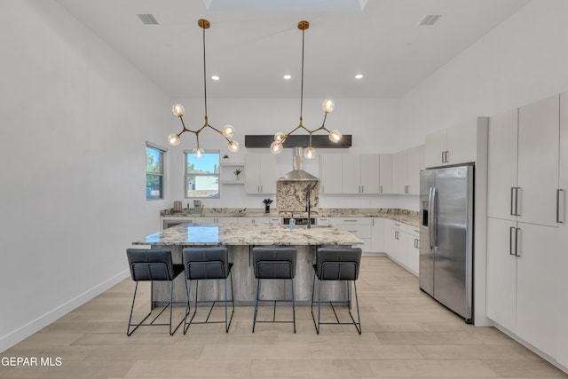 kitchen with light wood finished floors, a towering ceiling, white cabinetry, and stainless steel fridge with ice dispenser