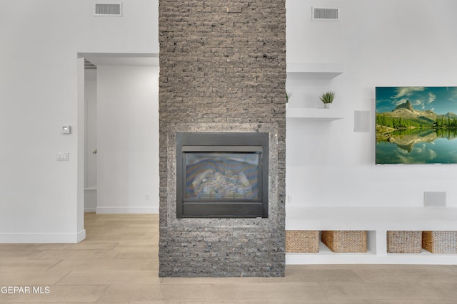 unfurnished living room with baseboards, visible vents, a glass covered fireplace, and wood finished floors