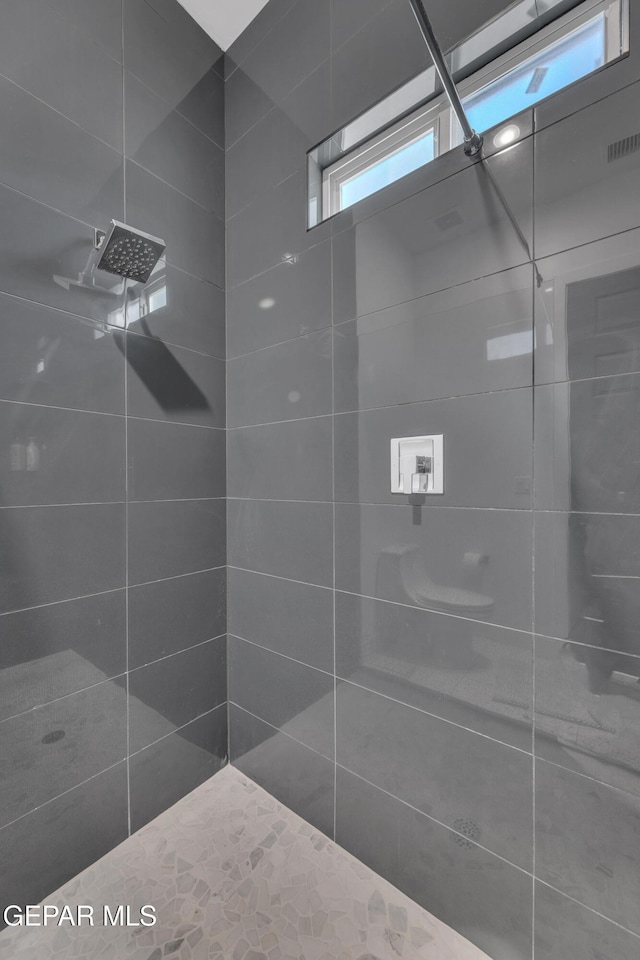 full bathroom featuring a tile shower and visible vents