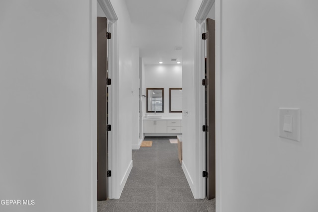 hall with baseboards, a sink, and granite finish floor
