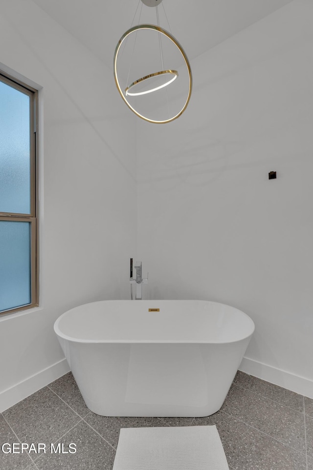 full bath featuring a freestanding bath and baseboards