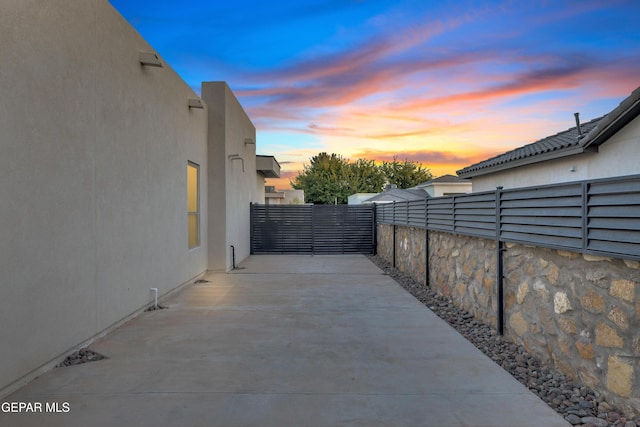 view of side of home with stucco siding, a patio area, and fence