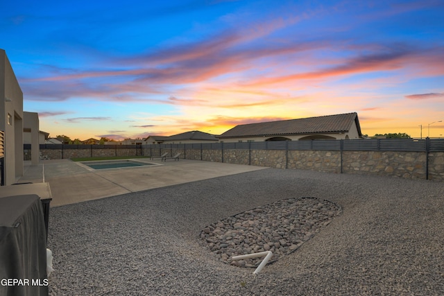 yard at dusk featuring a patio, a fenced in pool, and a fenced backyard