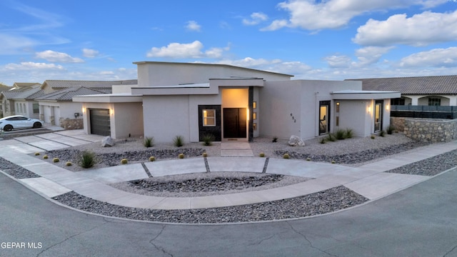 modern home with an attached garage, driveway, and stucco siding